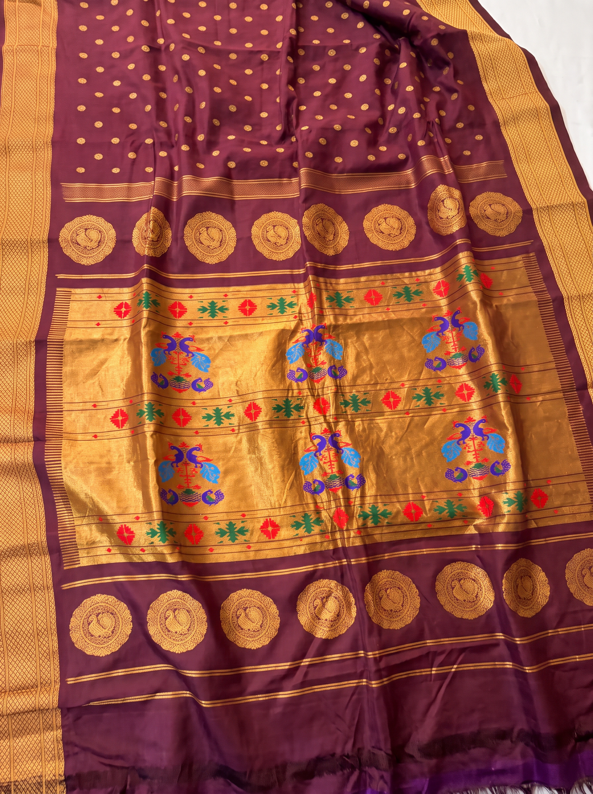 Rich as a first sip of coffee, touched with gold butas and a peacock border. The pallu shines in gold, where pairs of colourful peacocks meet above a violet fringe. Handloom Gadwal silk.