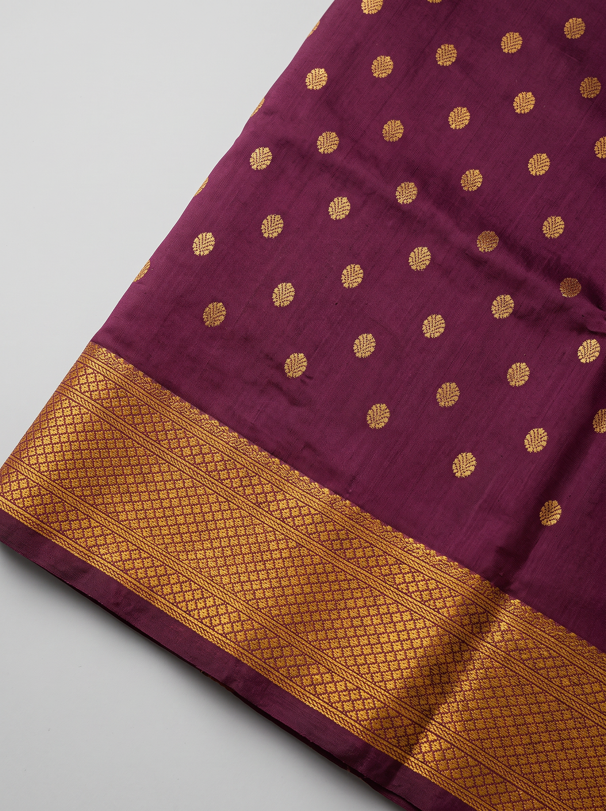 Rich as a first sip of coffee, touched with gold butas and a peacock border. The pallu shines in gold, where pairs of colourful peacocks meet above a violet fringe. Handloom Gadwal silk.