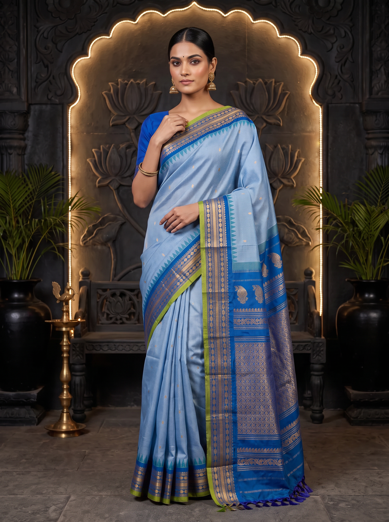 Soft as a morning sky, powder blue silk scattered with gold, deepening into royal blue where zari peacocks rest in a golden jaal. Handloom Gadwal.