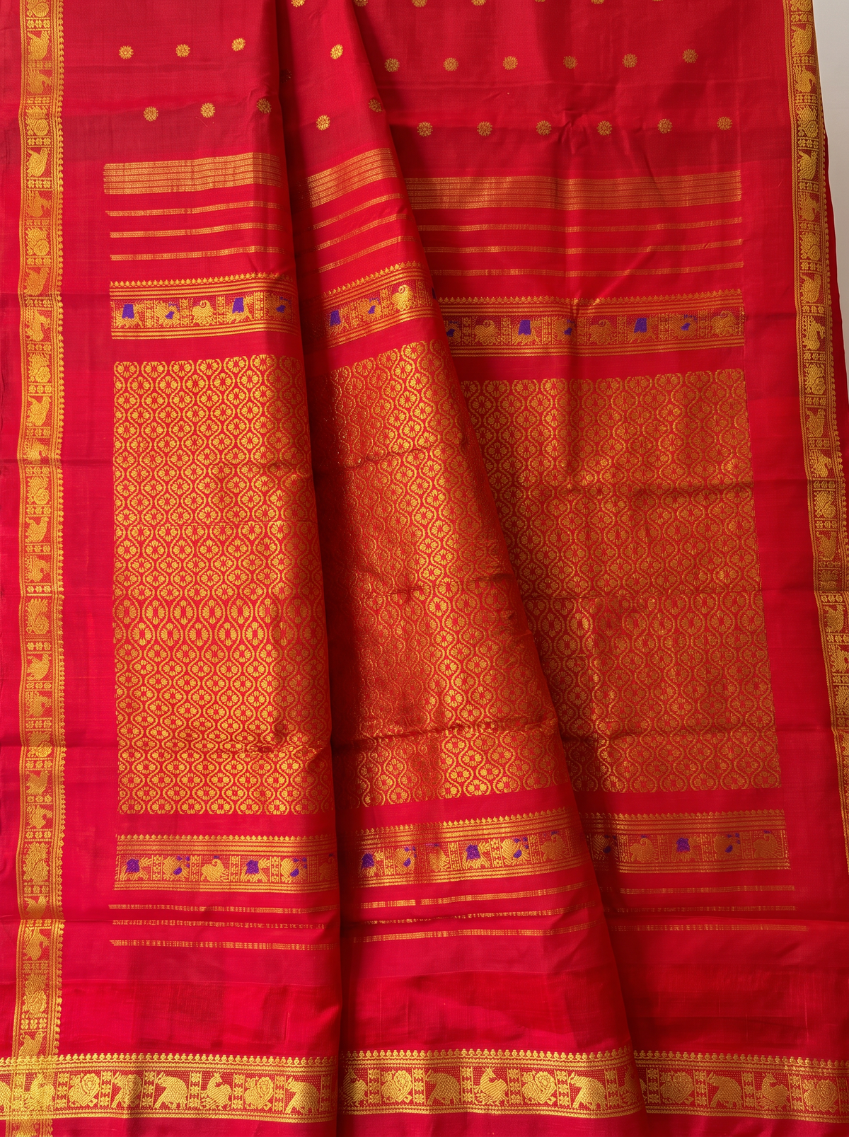 A timeless bridal red, glinting with gold. Handloom Gadwal silk with delicate buttis and a golden jaal border and pallu.