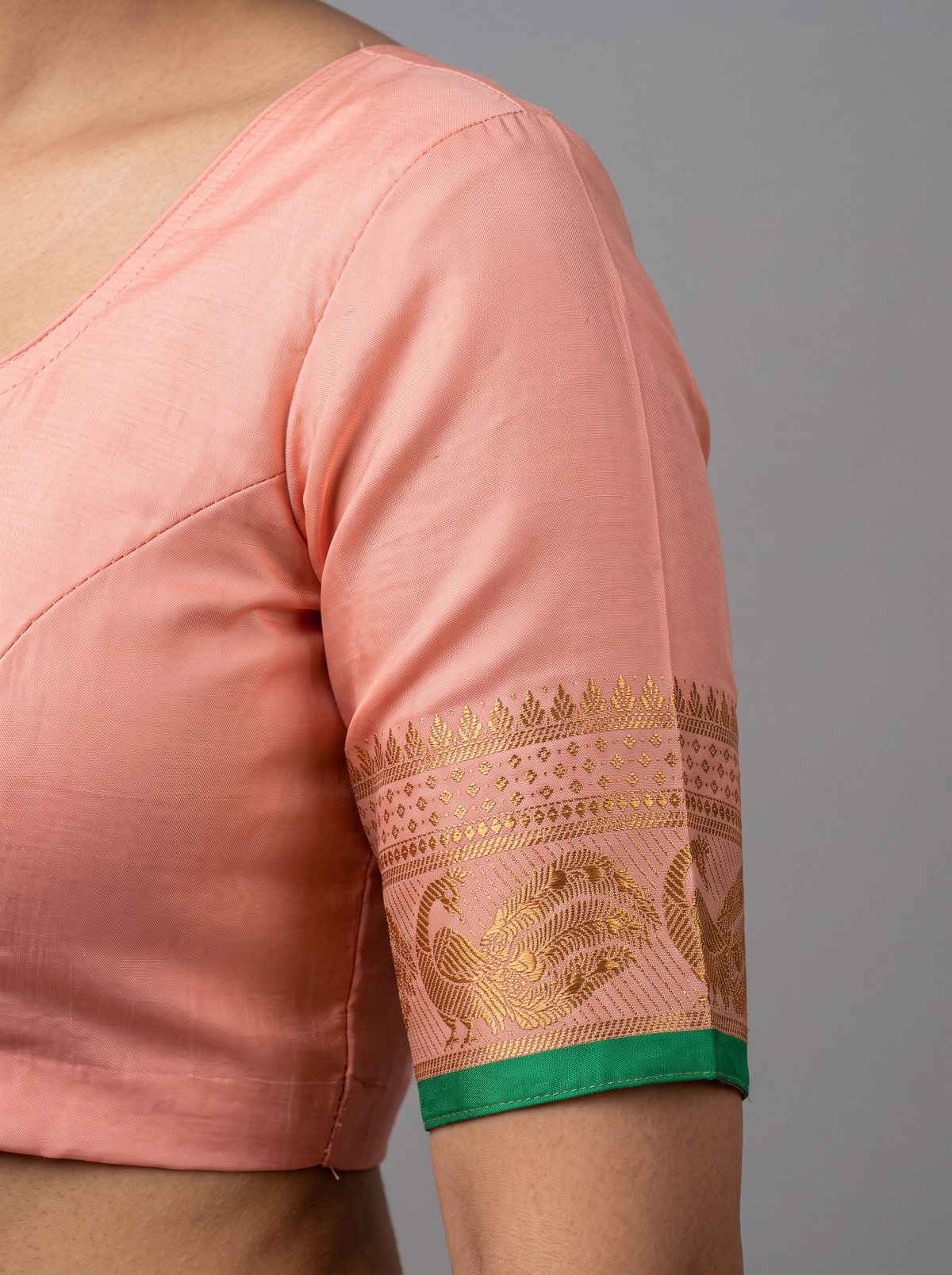 A blush of pink, a sprinkle of gold and teal, and peacocks in shimmering zari dancing along a green edge. Pure silk Gadwal, handwoven with love in Telangana.