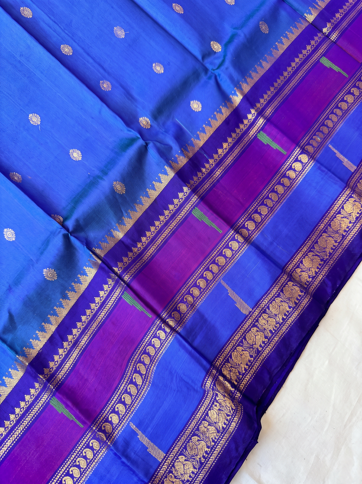 Like a clear midnight sky sprinkled with golden stars, this blue Gadwal silk is edged with peacocks and a blush of pink, finishing in a pallu rich with gold zari.