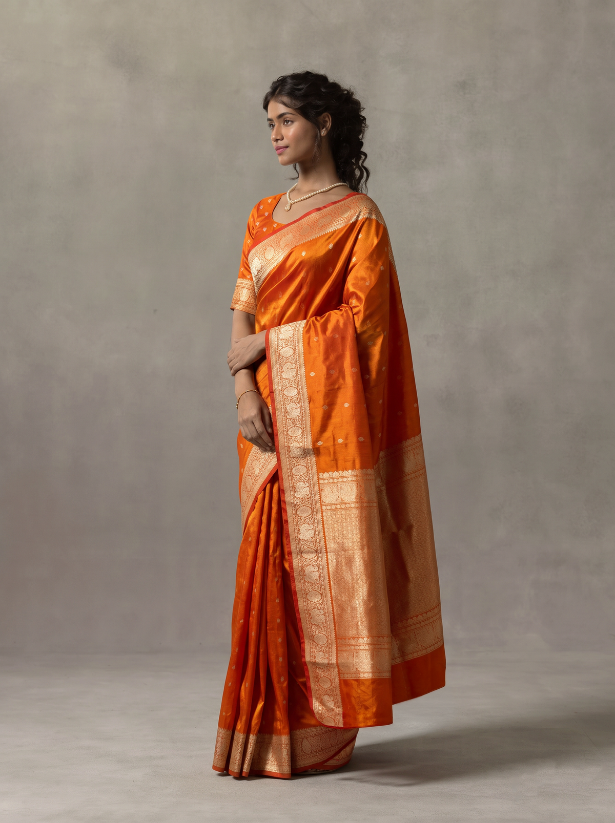 Like firelight caught in silk, orange-gold tissue glints with silver butas, while red peacocks guard the border and the golden pallu glows with lattice and a red fringe. Handloom Gadwal.