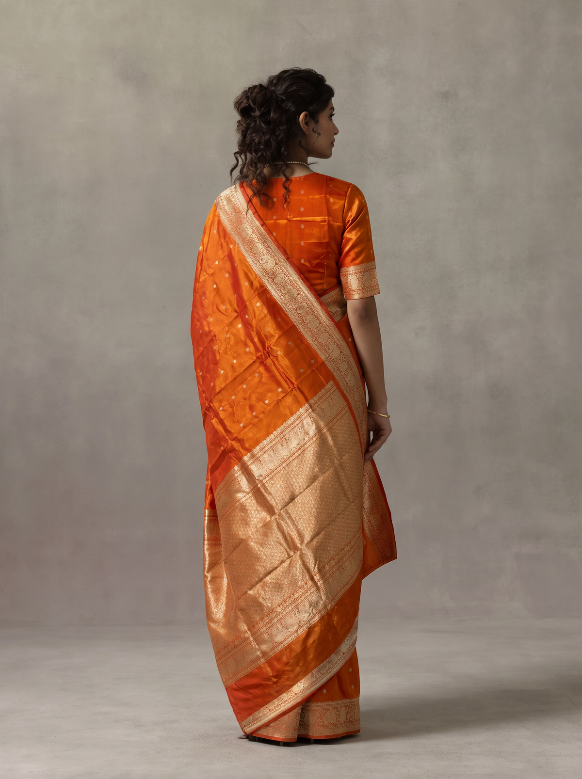 Like firelight caught in silk, orange-gold tissue glints with silver butas, while red peacocks guard the border and the golden pallu glows with lattice and a red fringe. Handloom Gadwal.
