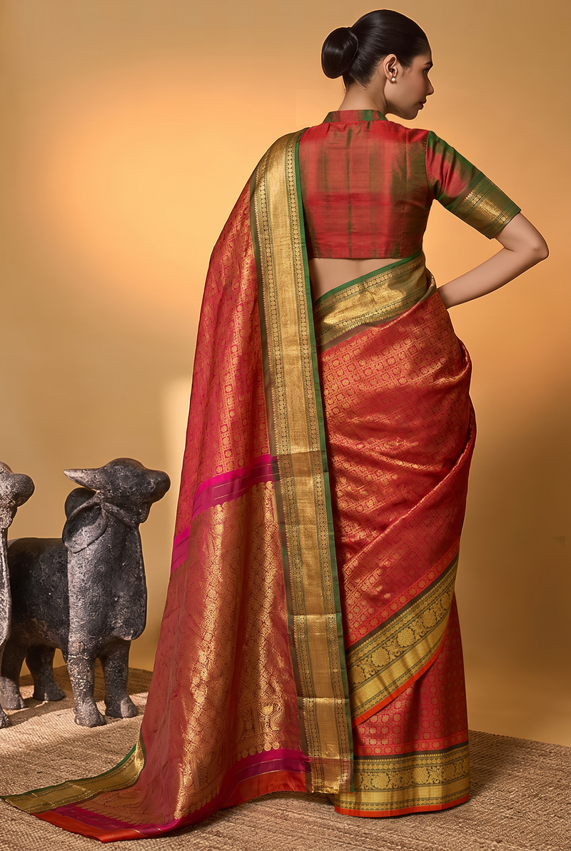 Like a lotus resting on dark leaves, vibrant pink silk glints with gold checks and opens into deep green, where brocade flowers glow in gold. Handloom Gadwal.