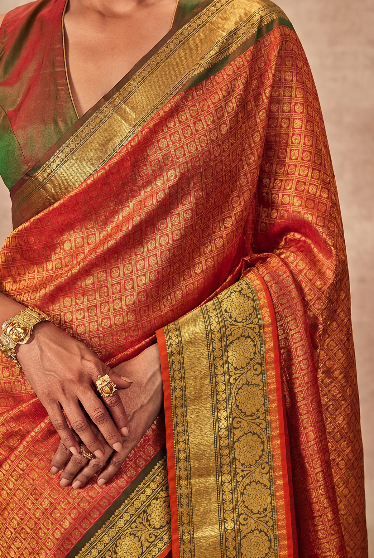 Like a lotus resting on dark leaves, vibrant pink silk glints with gold checks and opens into deep green, where brocade flowers glow in gold. Handloom Gadwal.
