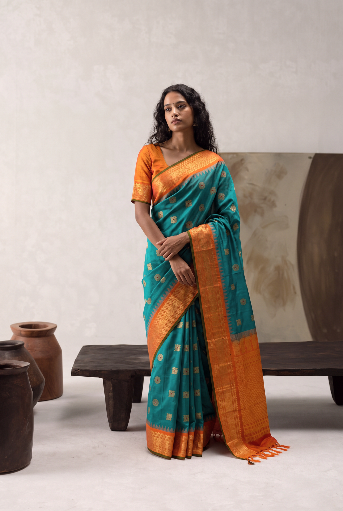 Rich teal, jewelled with ruby-dotted gold butas. A tissue-gold border that glows like liquid light, laced with diamond lattice and temple guards. Silk Mark certified handloom Gadwal silk from Telangana.