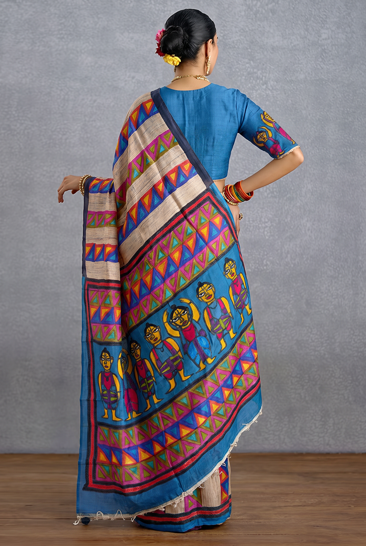 Beige-gold Tussar meets a slate blue field, where hand-stitched folk figures dance in rows, framed by bright bands of geometric triangles. Silk Mark certified handcrafted Tussar silk Kantha.